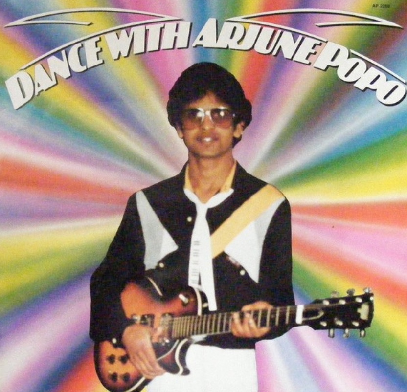 Front cover of the LP Dance With Arjune Popo: Arjune with sunglasses and an electric guitar against rainbow rays